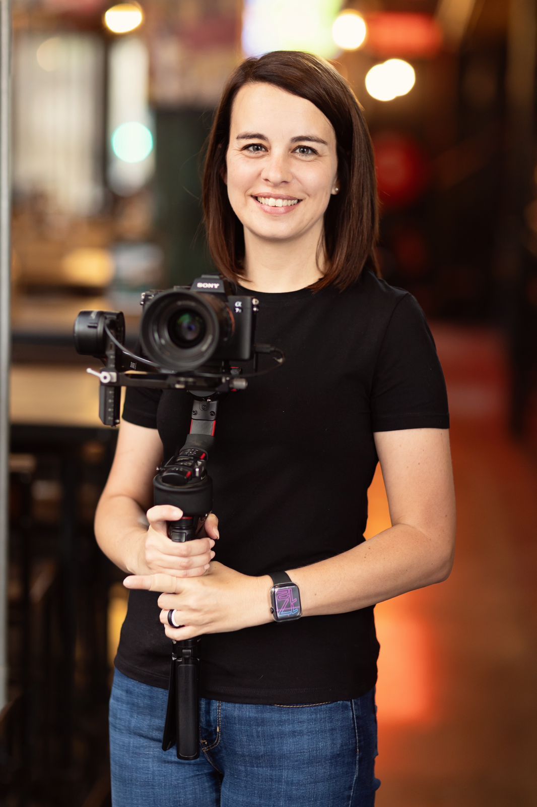 A photographer holds a professional camera with stabilizer in an indoor setting.