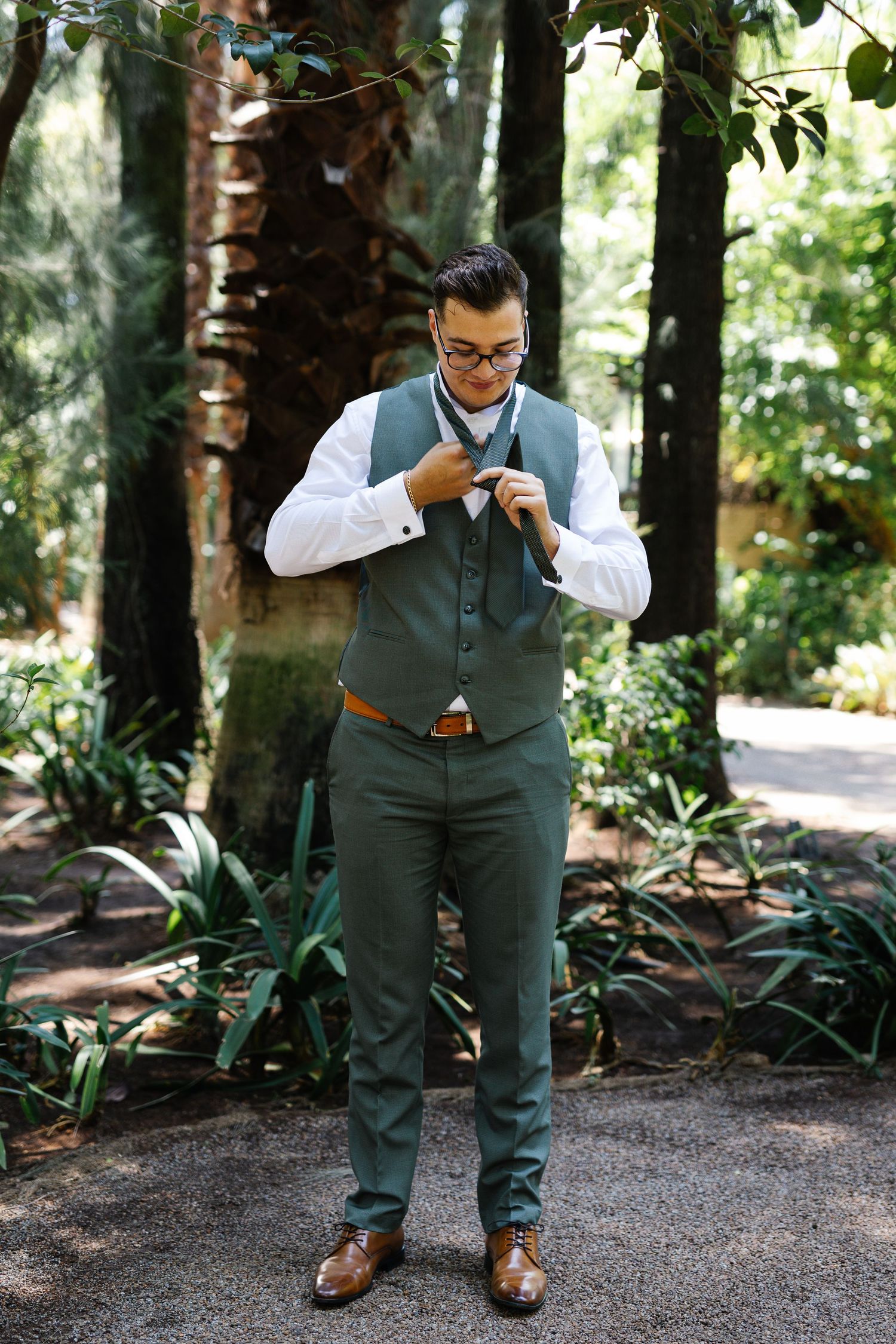 A sequence of photos showing a person in formal attire adjusting their outfit in a wooded outdoor setting.