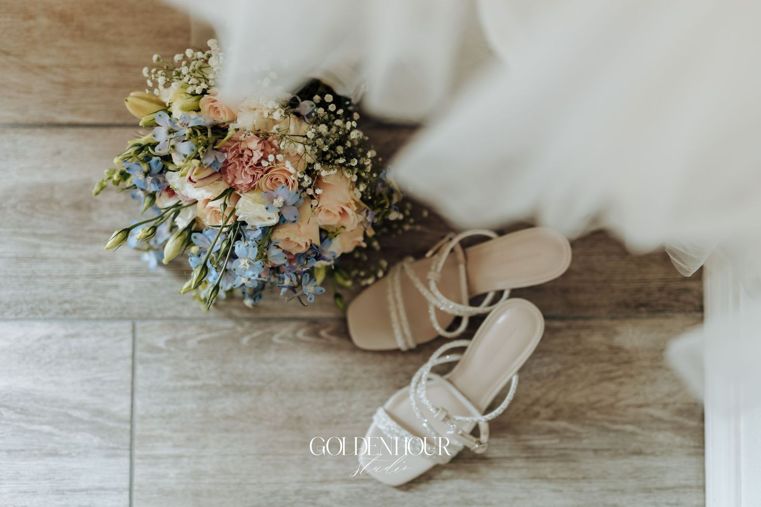 Delicate pastel floral bouquet with blue and peach blooms rests on rustic wooden surface.
