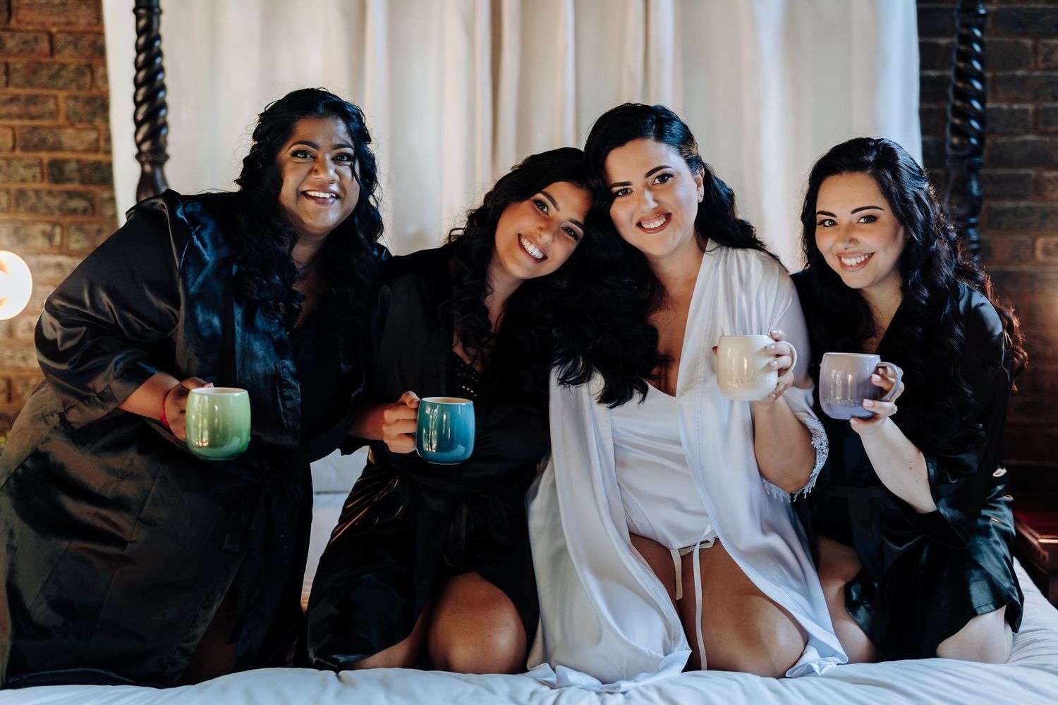 Wedding party enjoying drinks and laughter together in a rustic brick-walled room.