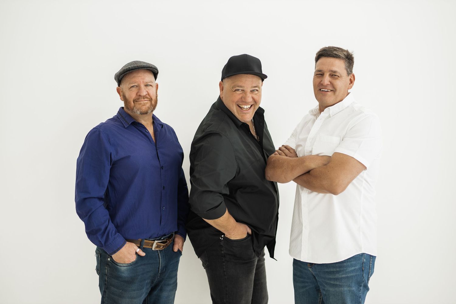 Three people smiling in casual outfits pose together against a white background.