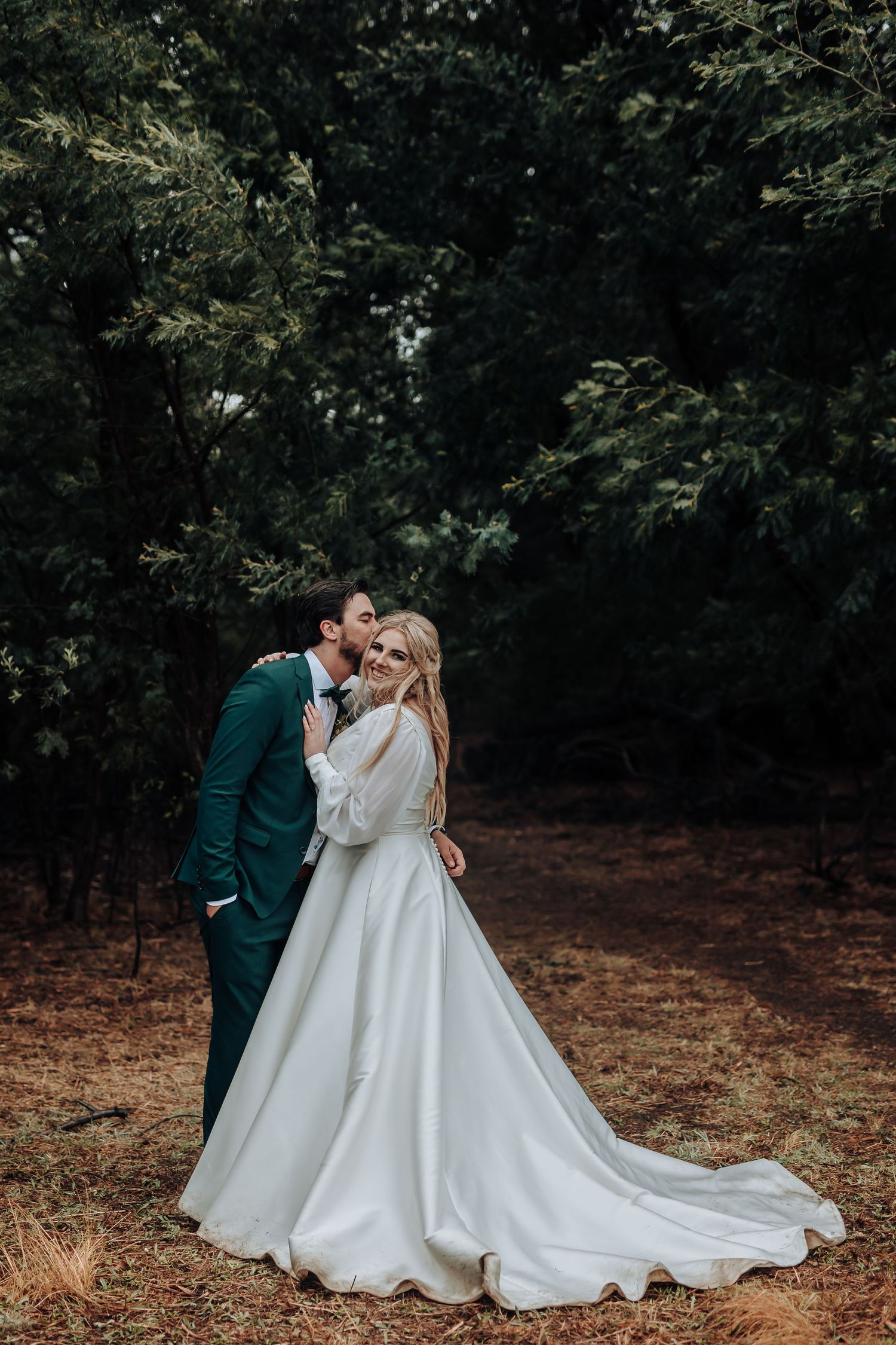 A tender moment between newlyweds captured in a serene forest setting.