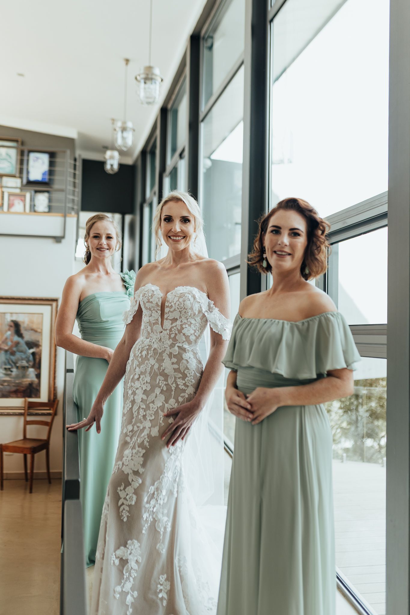 Wedding party poses in natural light by glass windows wearing mint and white formal attire.