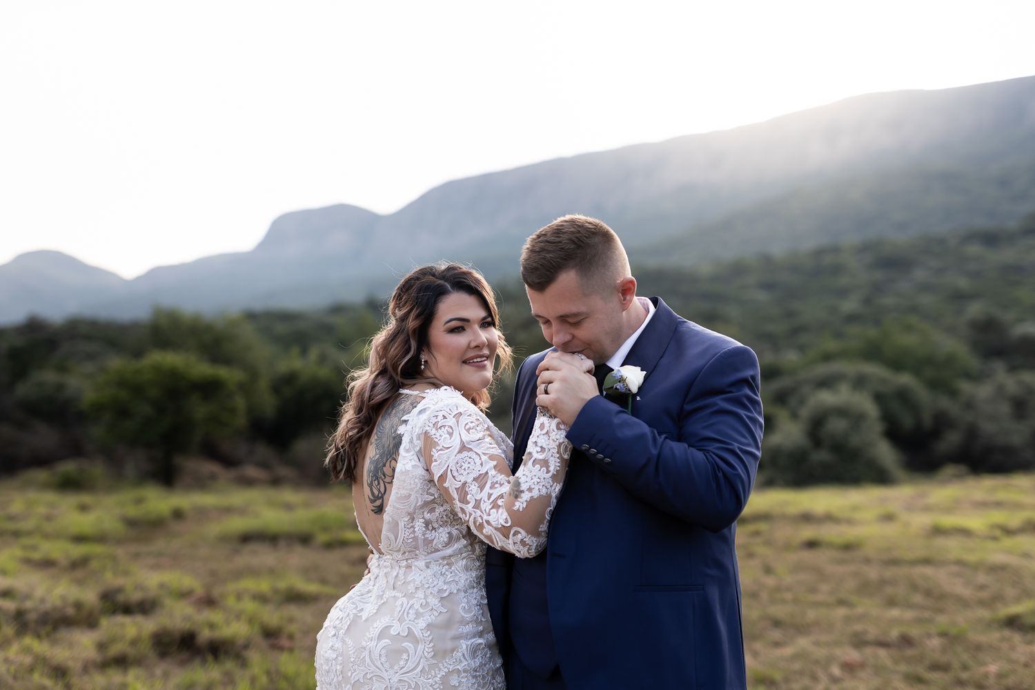 A tender moment between newlyweds in a mountainous field during golden hour.
