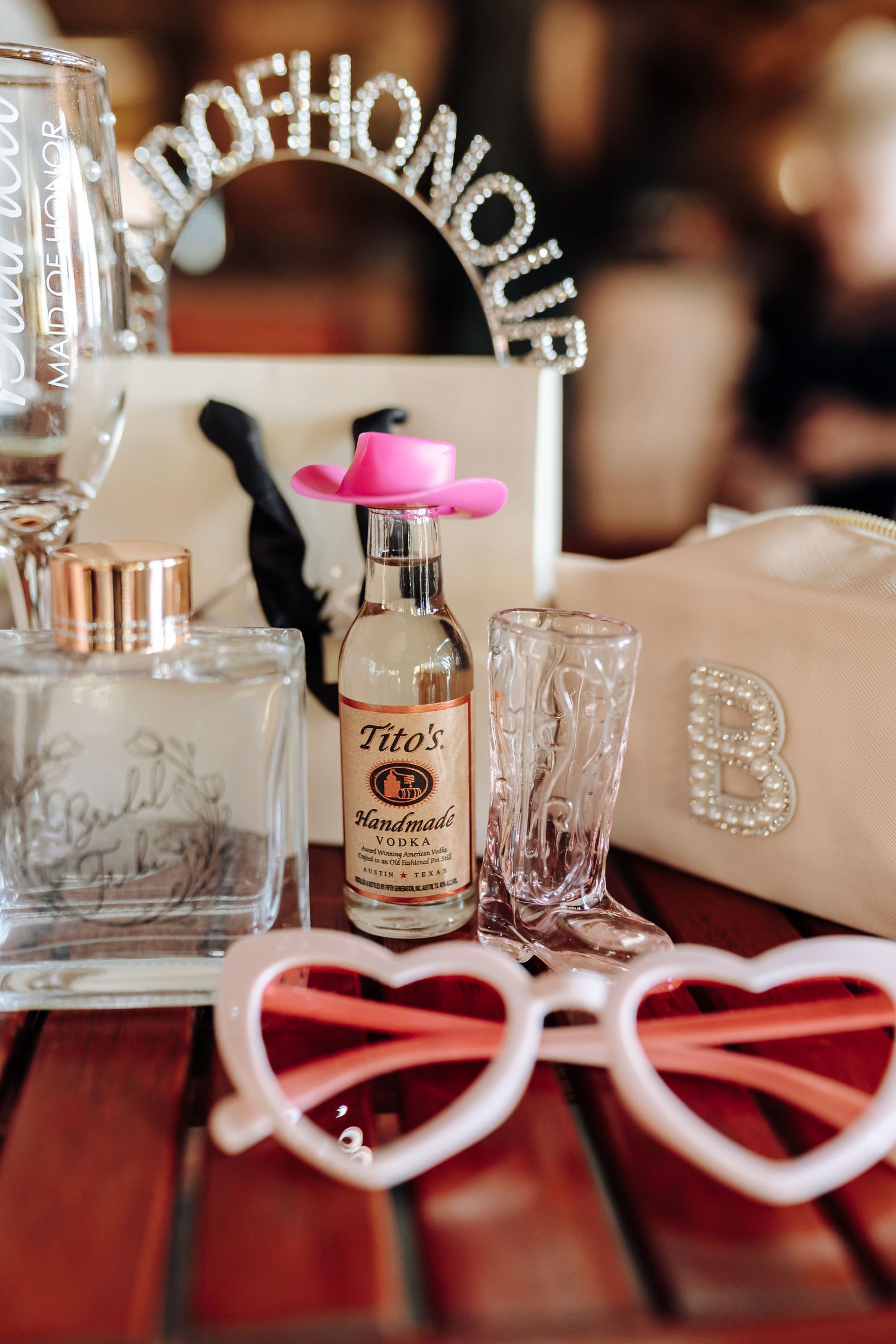 Heart-shaped sunglasses resting on a table next to vintage glassware and decorative bottles at a wedding reception.