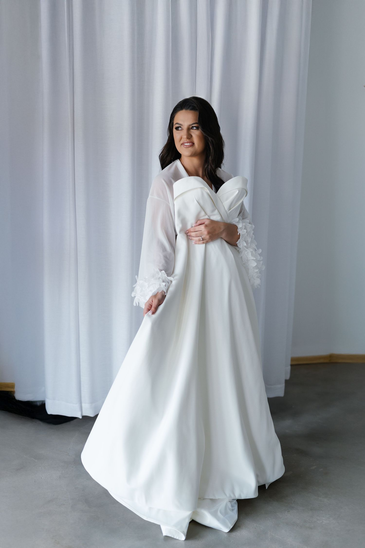 Model showcases a flowing white oversized dress with dramatic movement against a gray backdrop in multiple poses.
