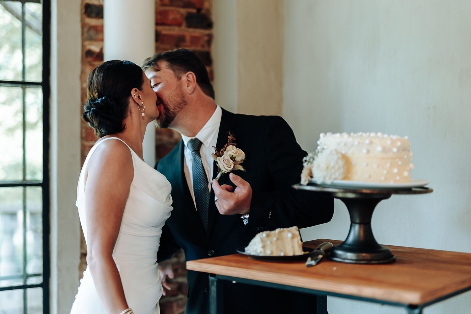 Couple sharing intimate moments during wedding reception at elegant venue with white decor and natural lighting.