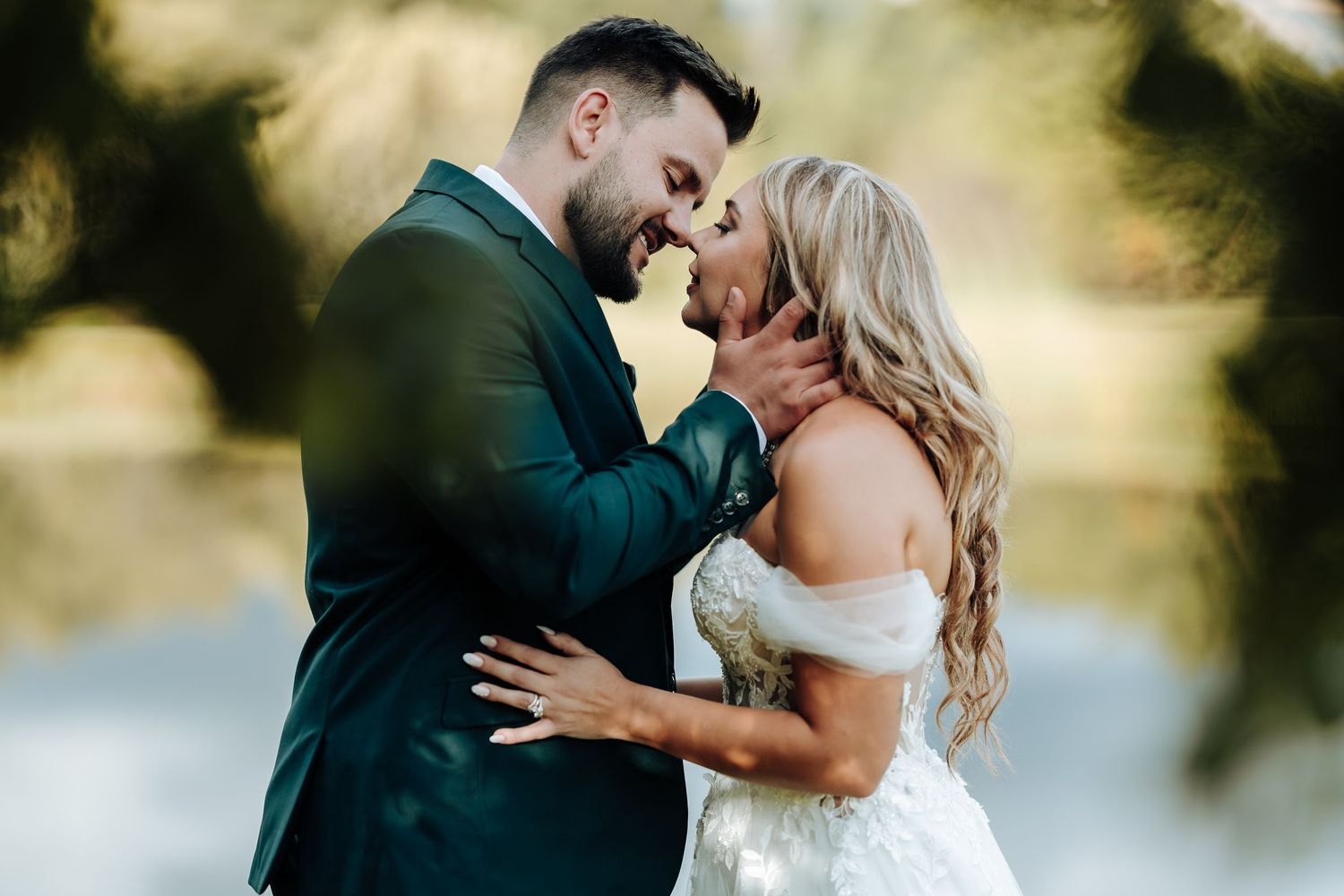 A romantic couple in formal wedding attire share intimate moments in a sunlit outdoor setting during their special day.