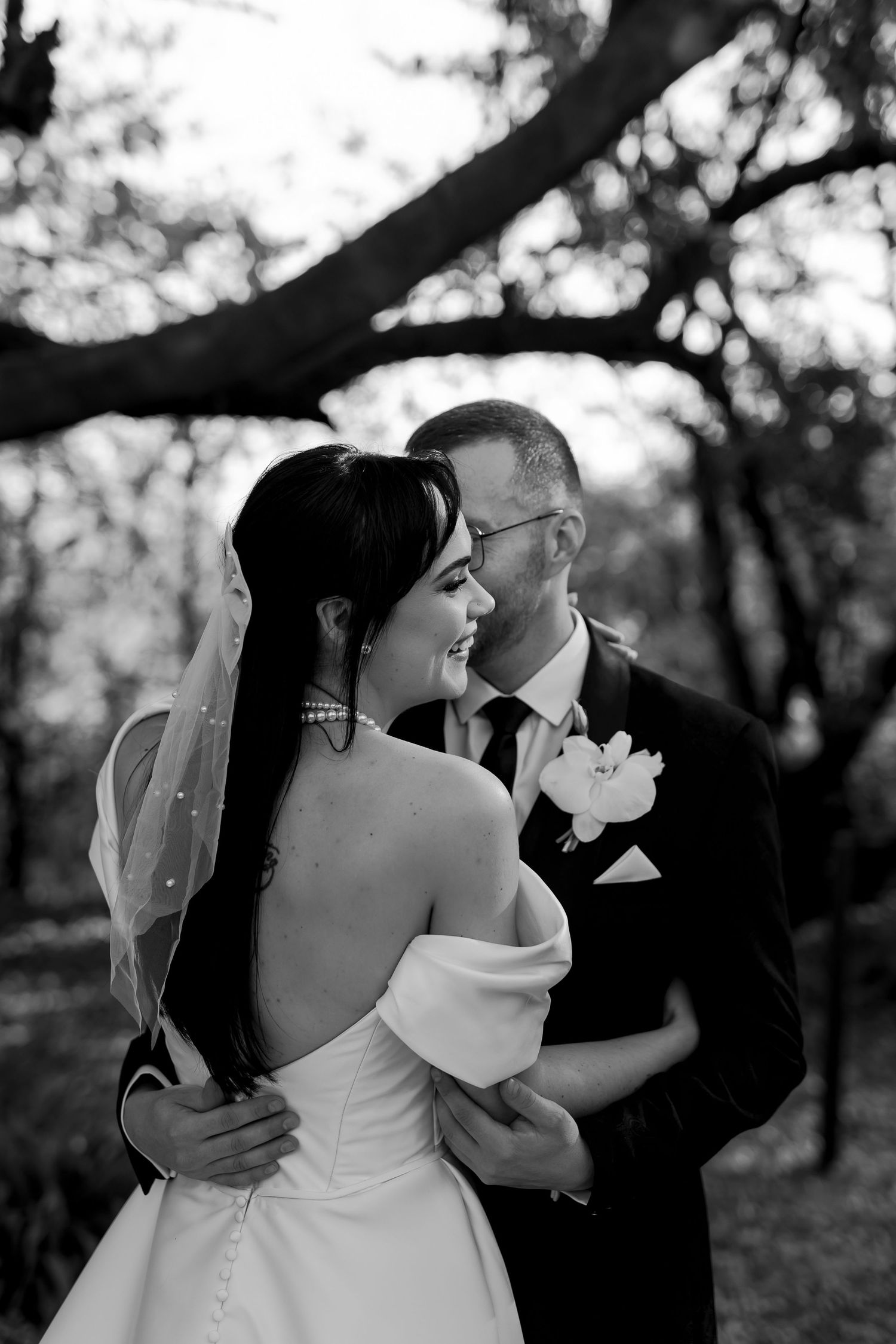 A bride and groom share an intimate black and white moment together outdoors during their wedding ceremony.
