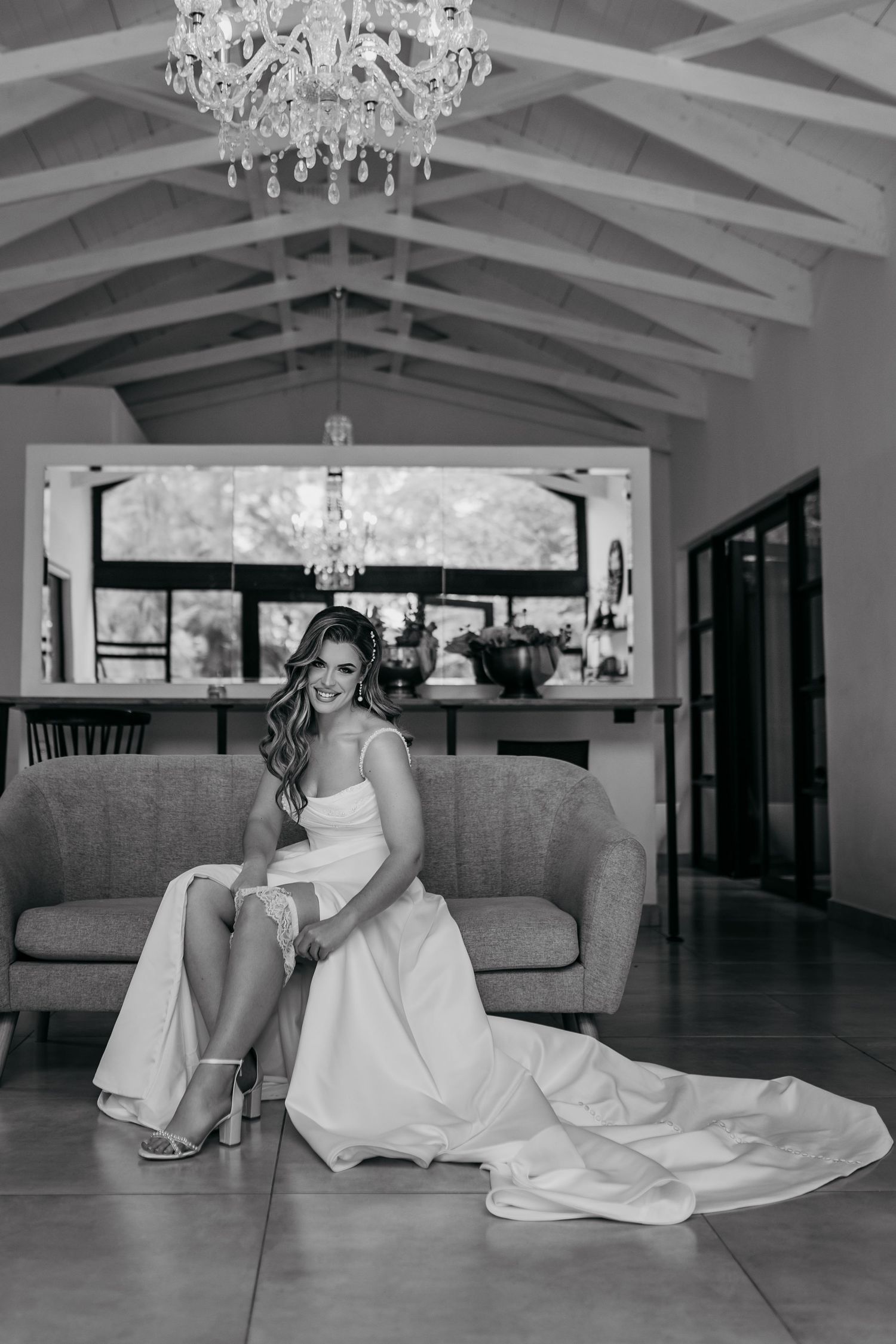 Elegant interior with vaulted ceiling, crystal chandelier and bridal portrait on grey couch.