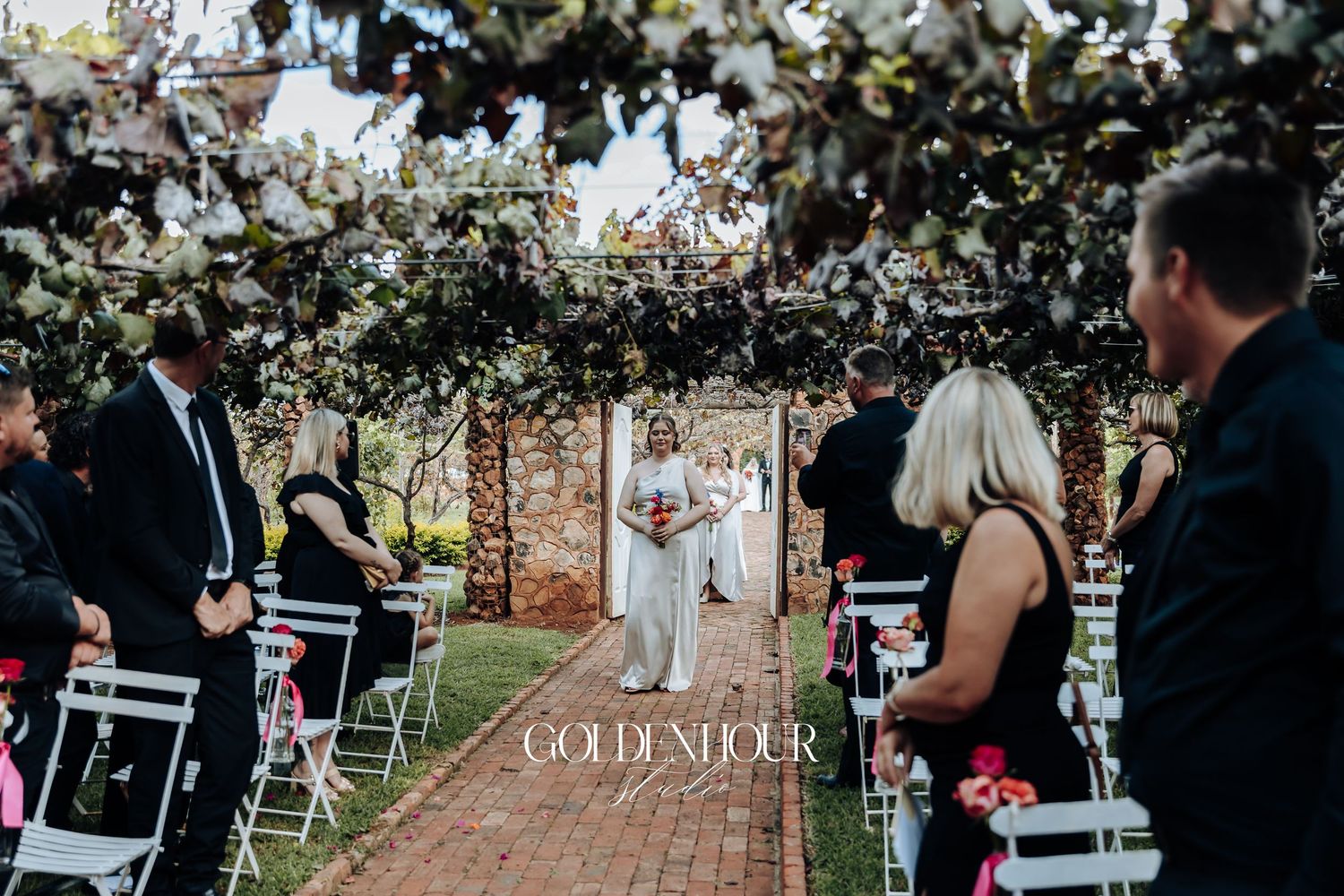 Guests seated at an outdoor wedding ceremony under blooming cherry blossom trees.