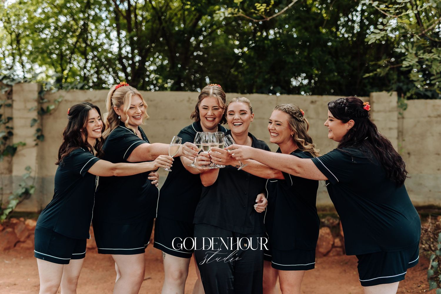A group of people wearing black shirts stand together outdoors in a celebratory pose.