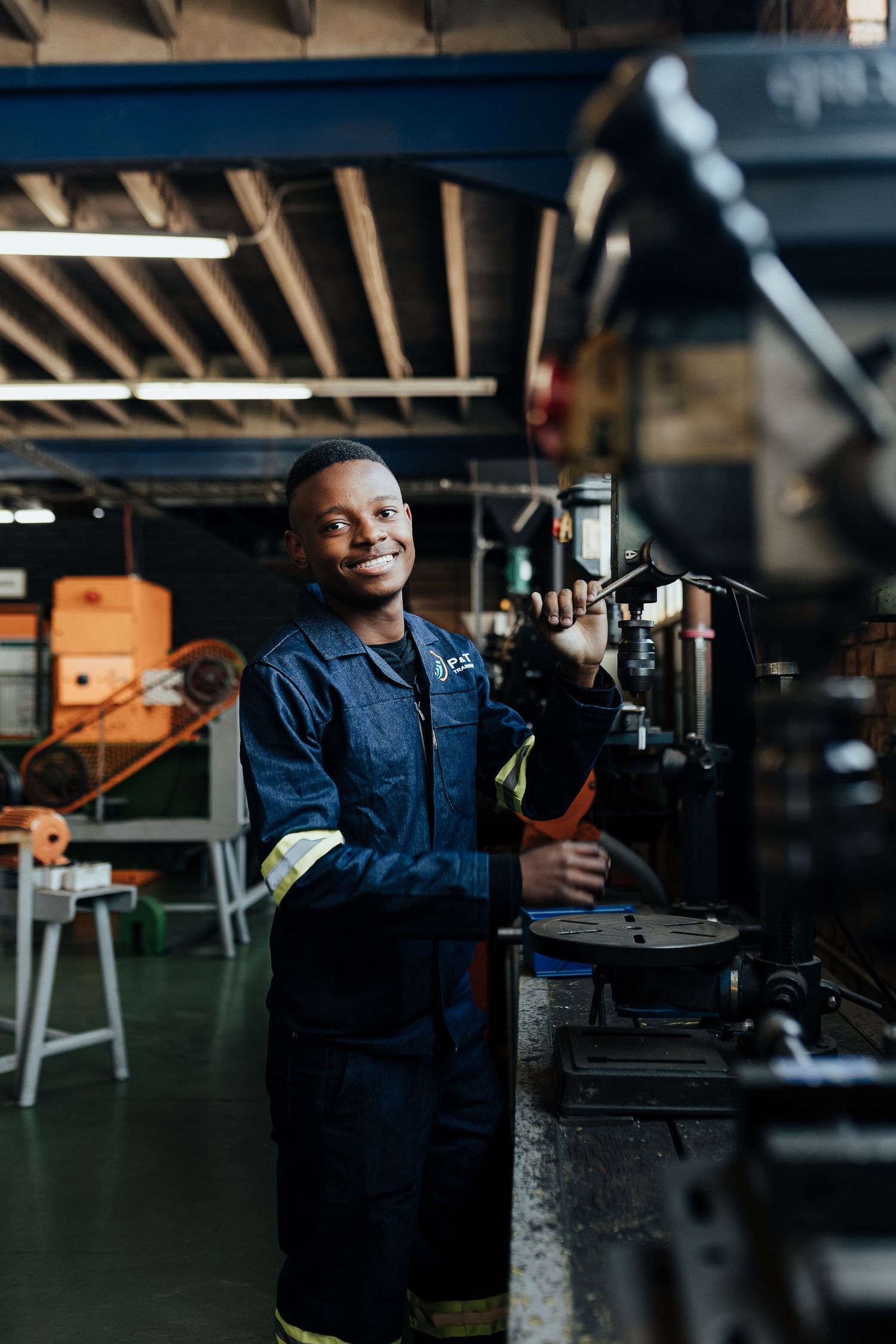 Industrial worker in blue uniform operates machinery in dimly lit factory setting using modern equipment.