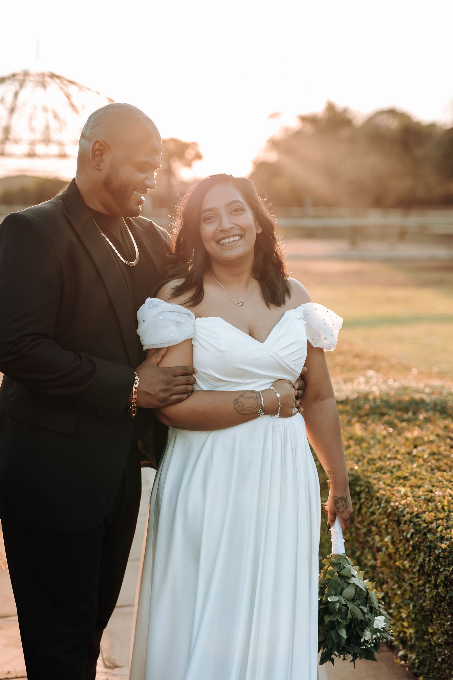 Joyful wedding couple laughing together during golden hour portrait session.