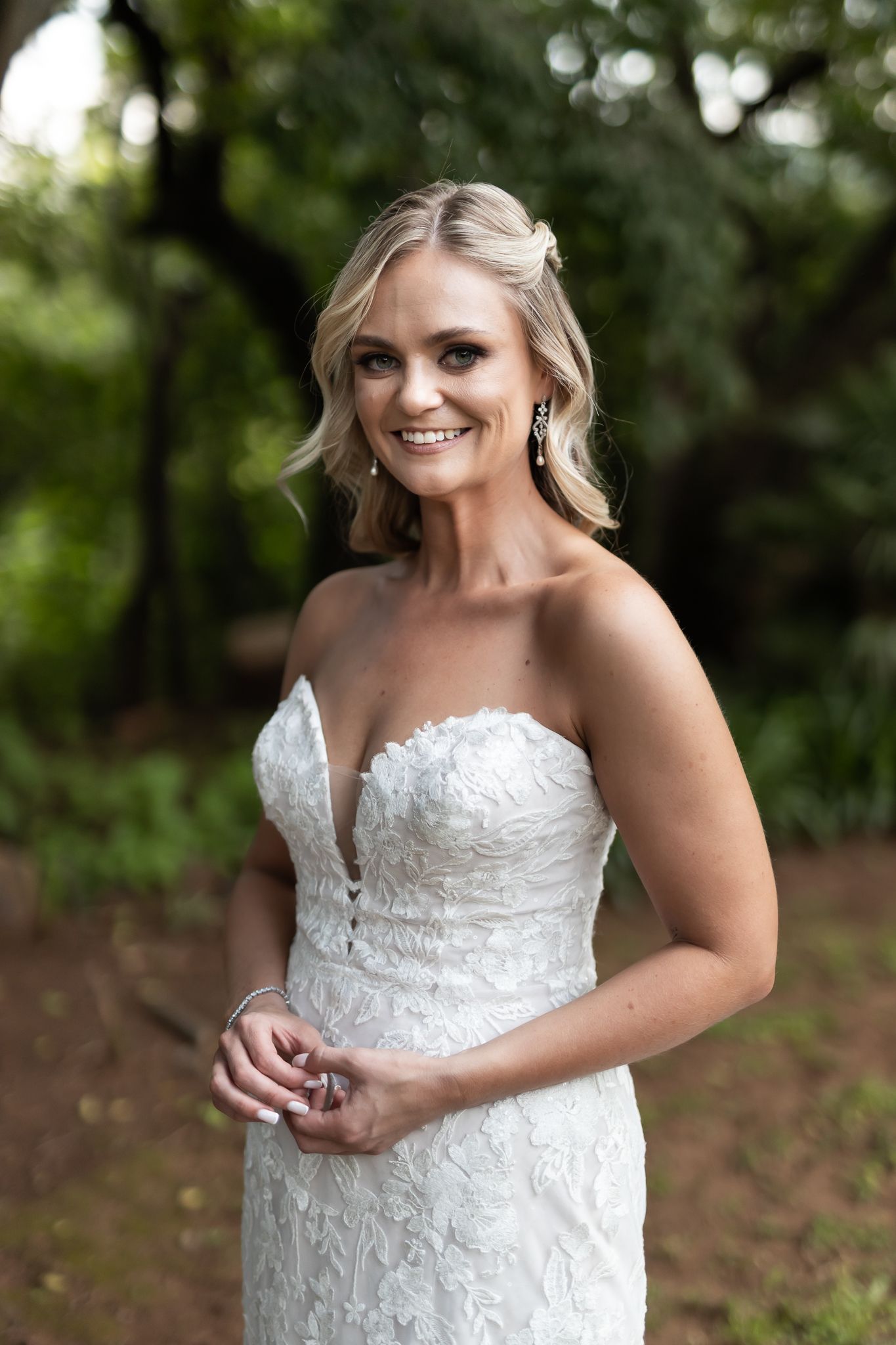 A bridal portrait in a white lace gown against a natural garden backdrop.