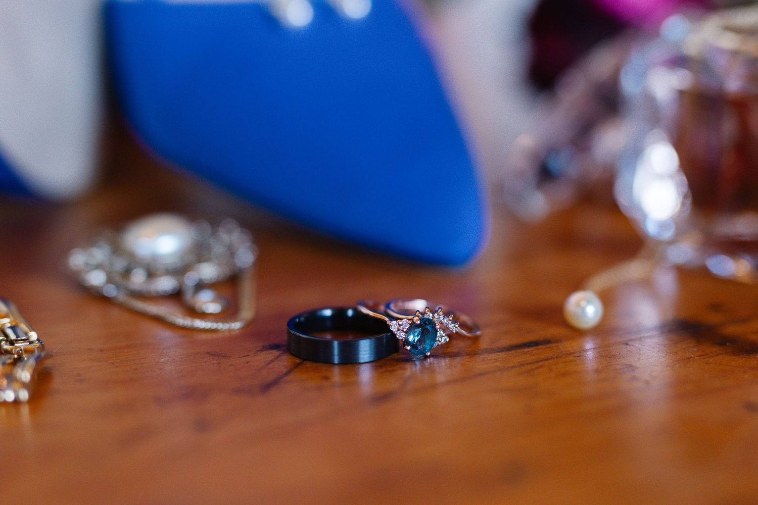 Wedding rings and jewelry arranged on a wooden surface with a blue accent in the background.