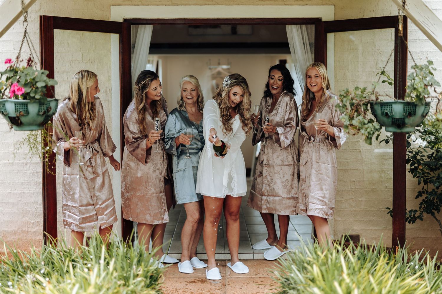 A group of bridesmaids in matching light-colored dresses pose together in a series of candid wedding photos.