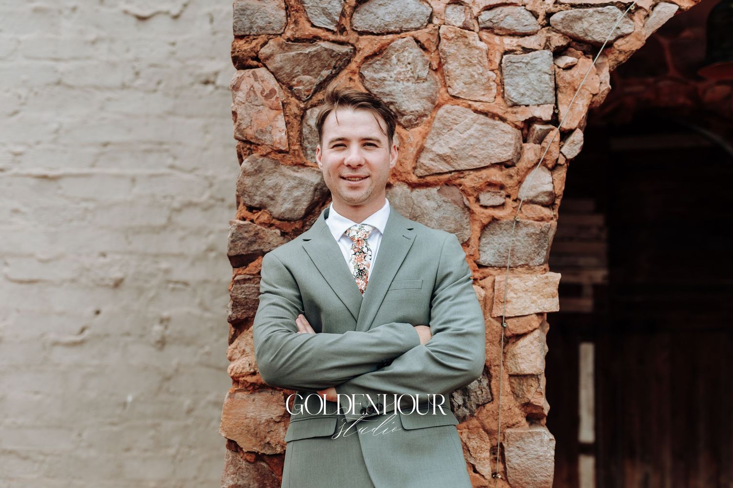 Person wearing mint green suit jacket stands confidently against textured stone wall.
