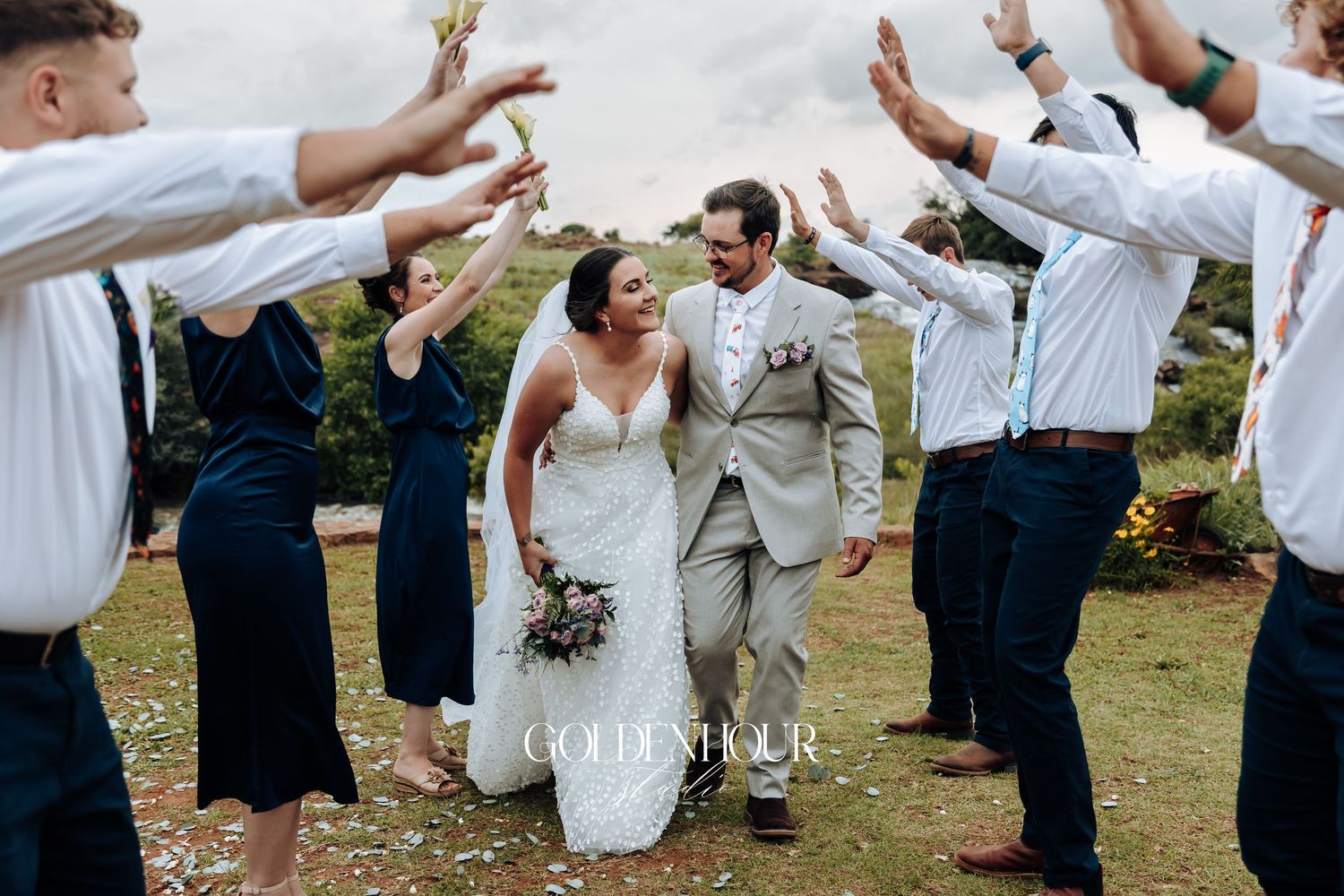 Wedding celebration with guests raising their arms in joyful celebration outdoors.
