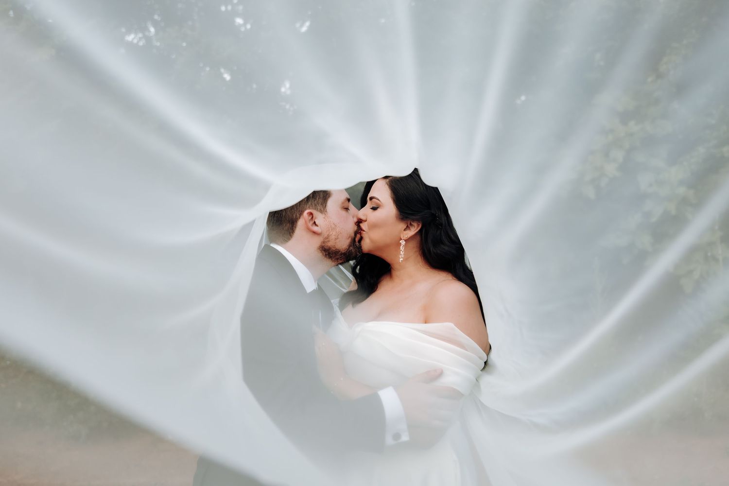 Silhouetted figures embracing against white flowing fabric backdrop.