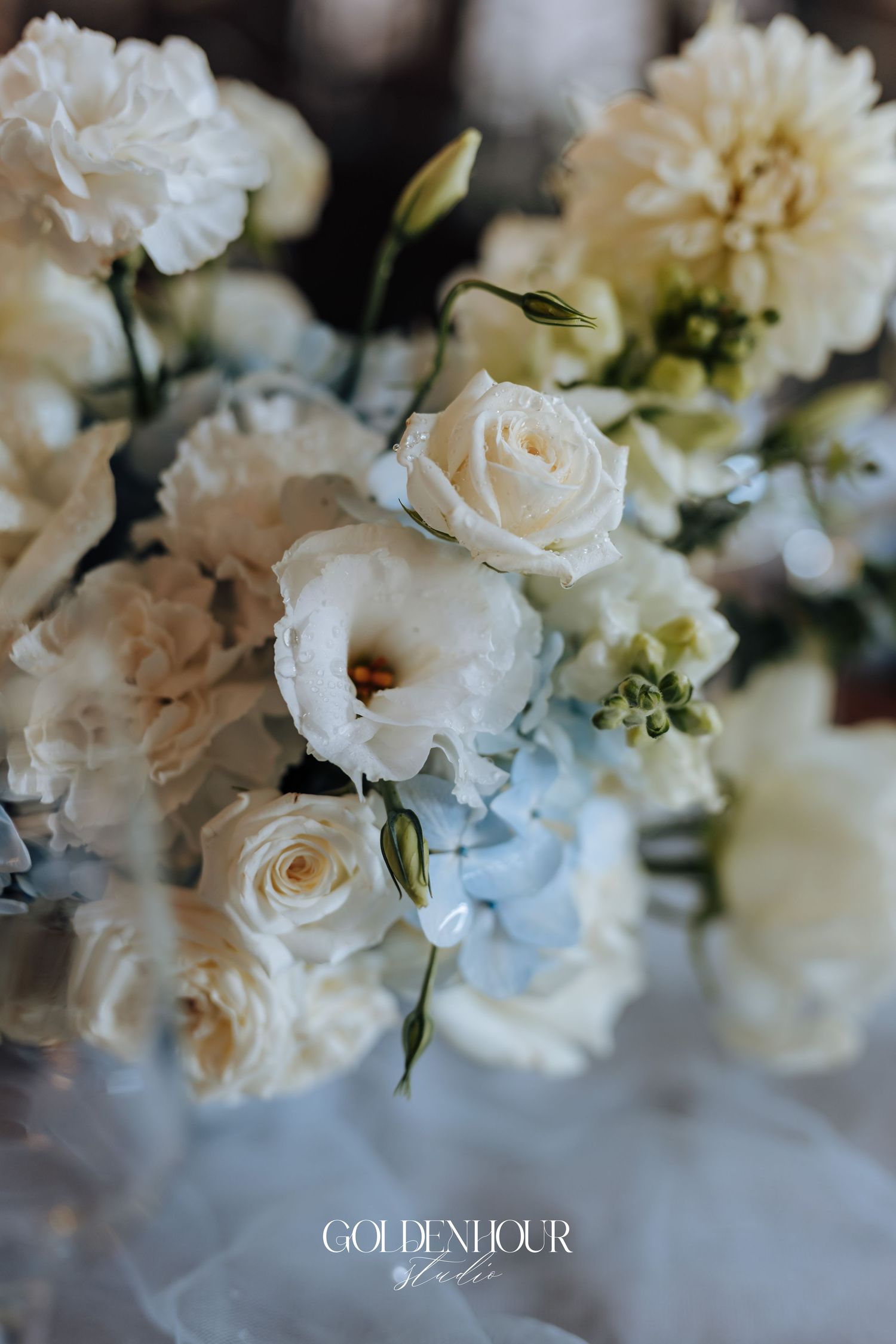 Elegant white roses and floral arrangements in soft focus create a romantic wedding atmosphere.