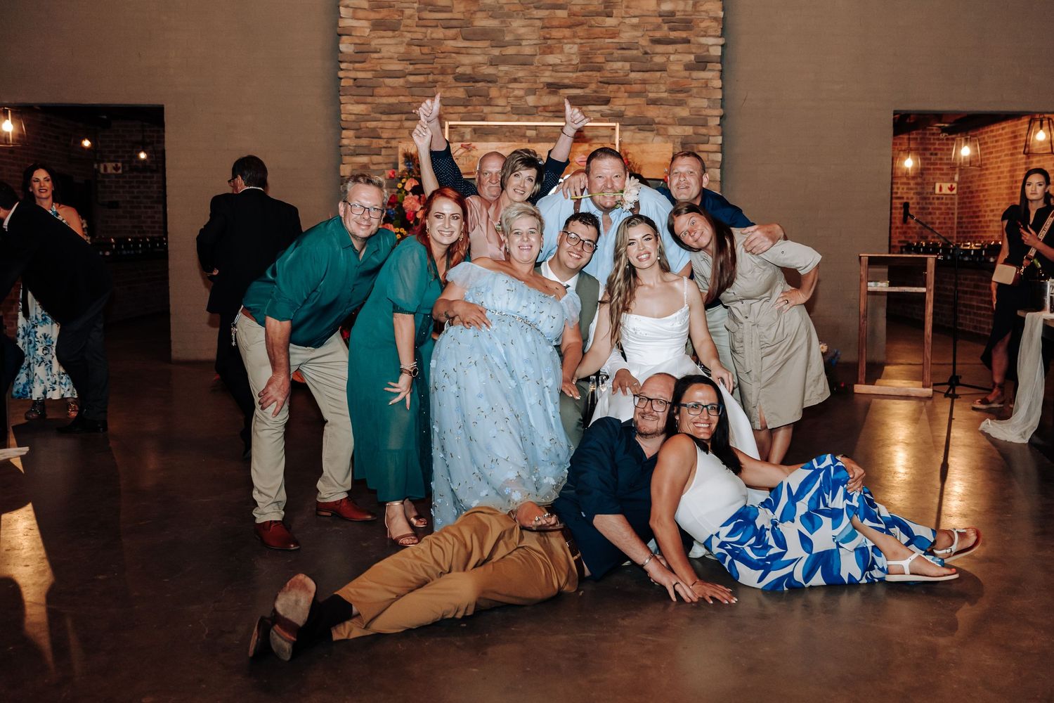 Wedding celebration panorama showing guests seated in a rustic venue with brick walls and ambient lighting.