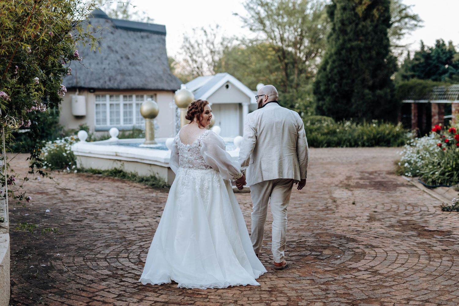 A romantic outdoor wedding scene with white dresses swirling in motion against a rustic stone pathway.