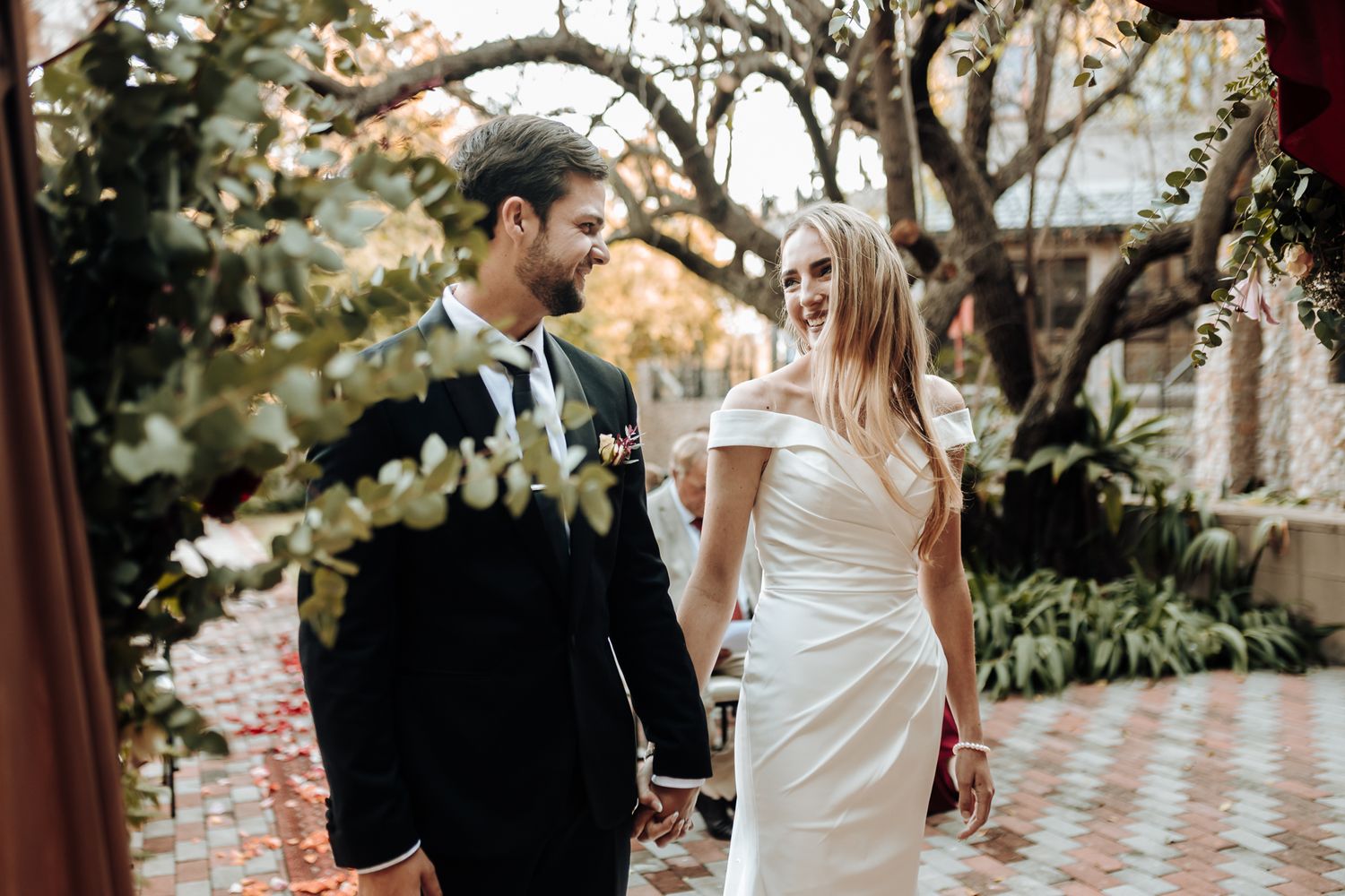 Elegant outdoor wedding portrait amid lush garden scenery and draped fabric decor.