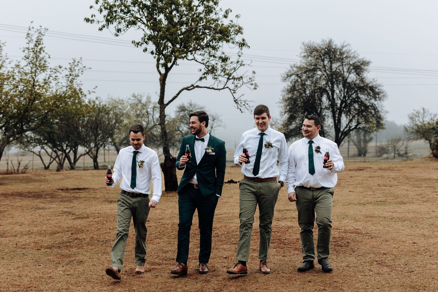 Wedding party walking together on rustic grounds wearing coordinated formal attire.