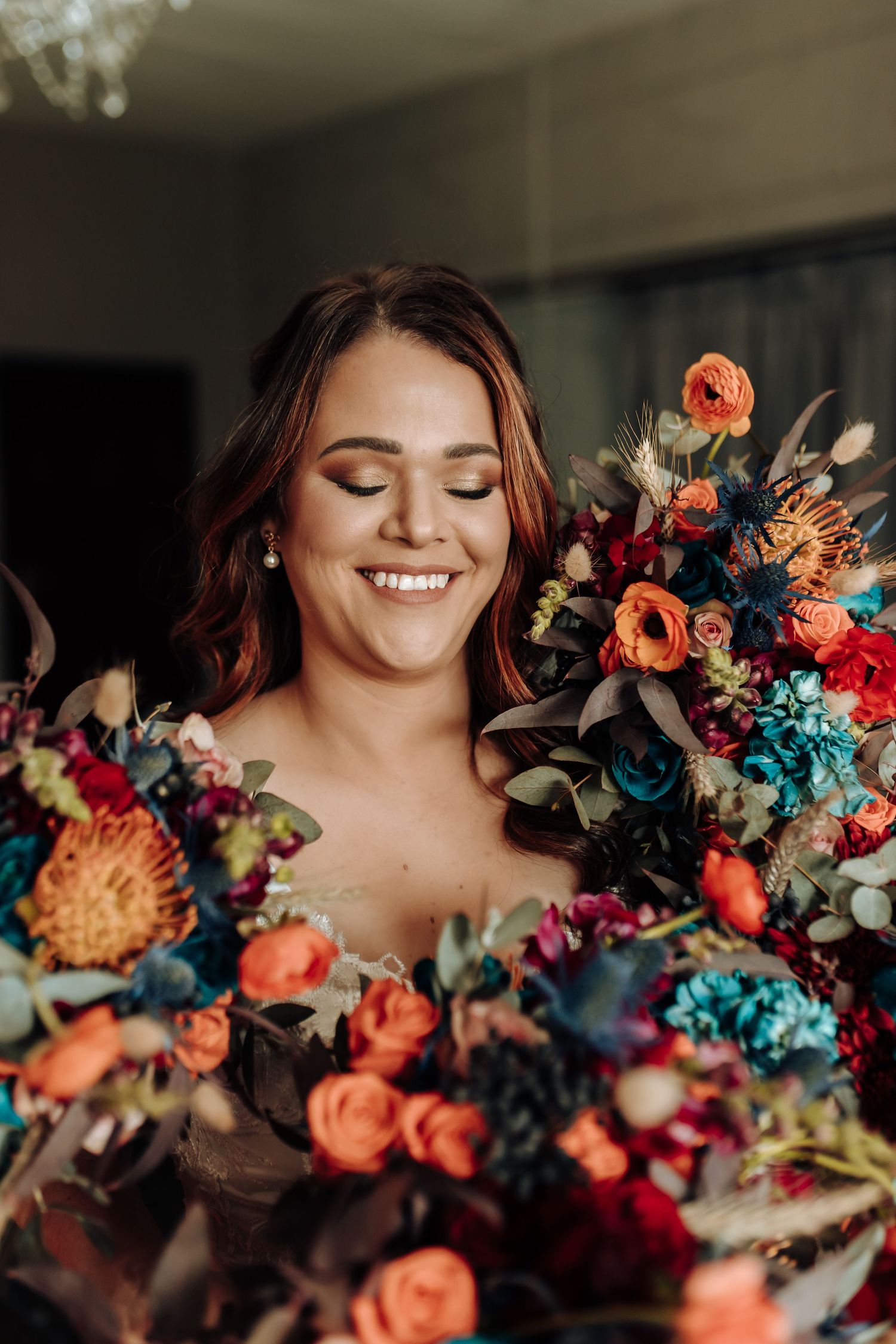 Close up of joyful moment with colorful wedding bouquet featuring coral roses and blue florals.