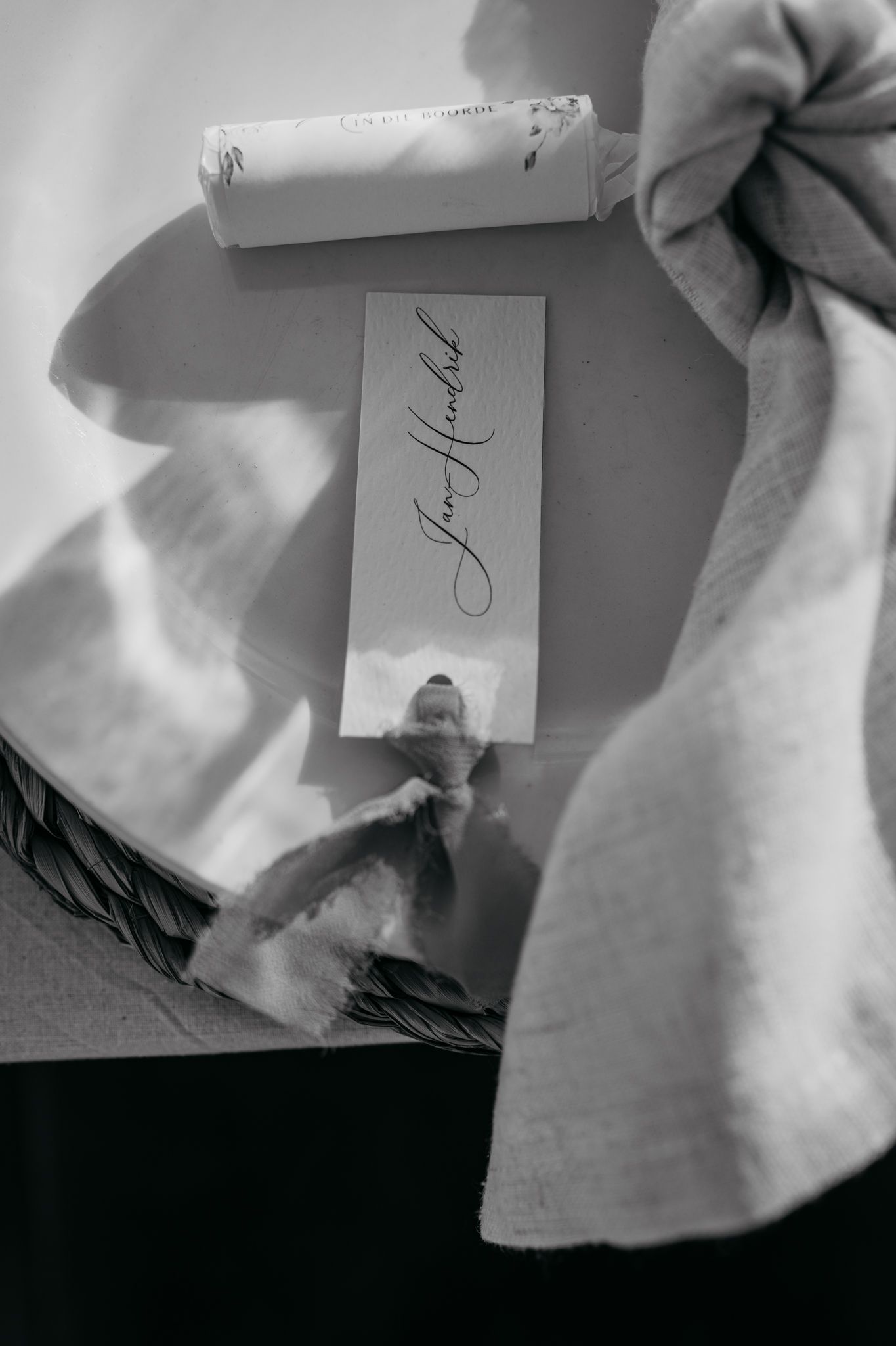 Black and white detail shot of place card and napkin on elegant table setting.