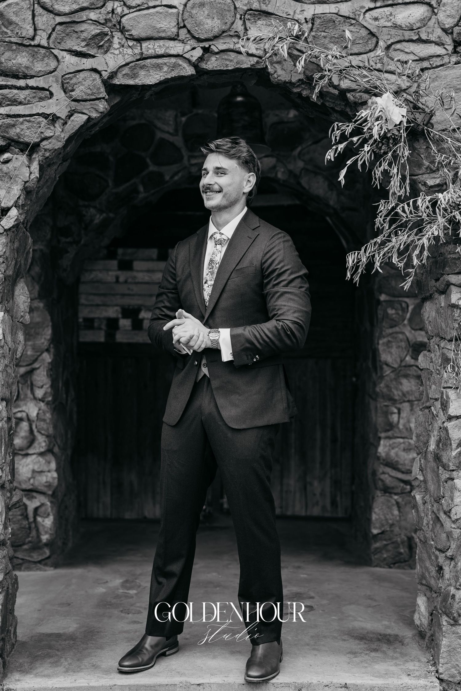 Black and white portrait series showing playful poses against a rustic stone archway background.
