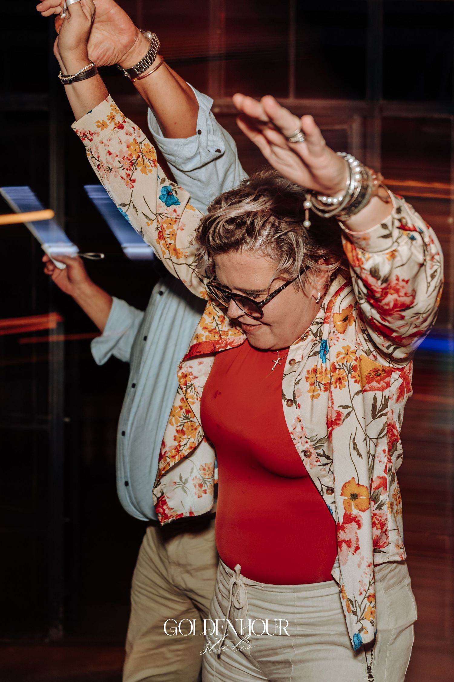 Guest in floral jacket and red top dancing energetically at lively wedding reception party.
