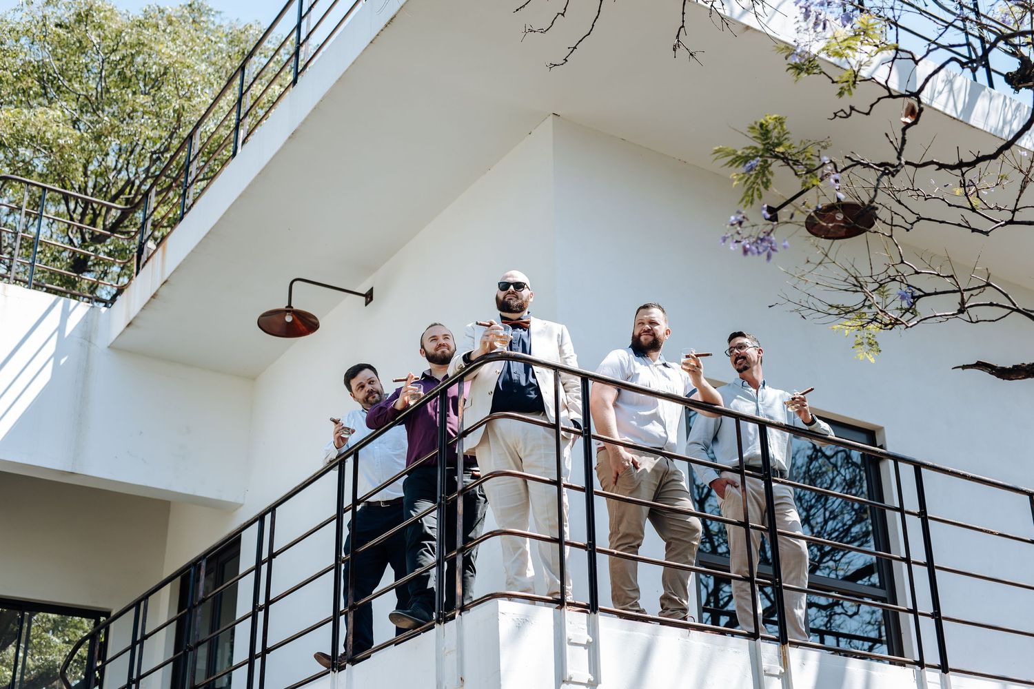 People standing on a white balcony with railings during a sunny day.