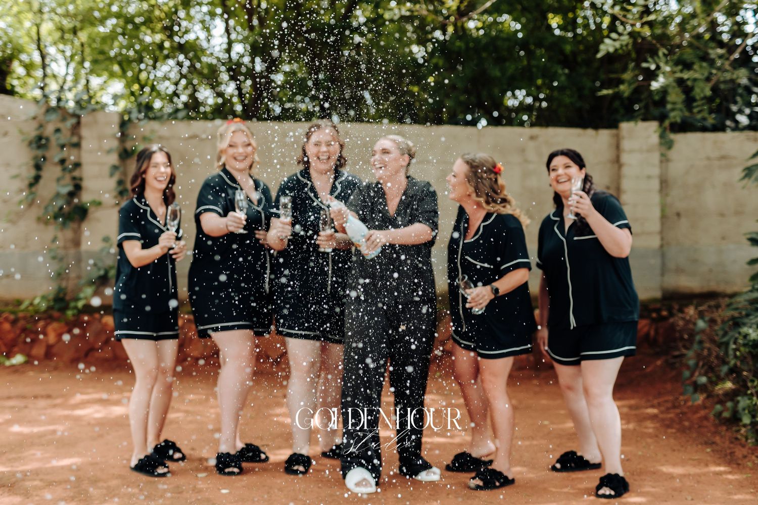 A group of people jumping and splashing water while wearing black outfits in an outdoor setting.
