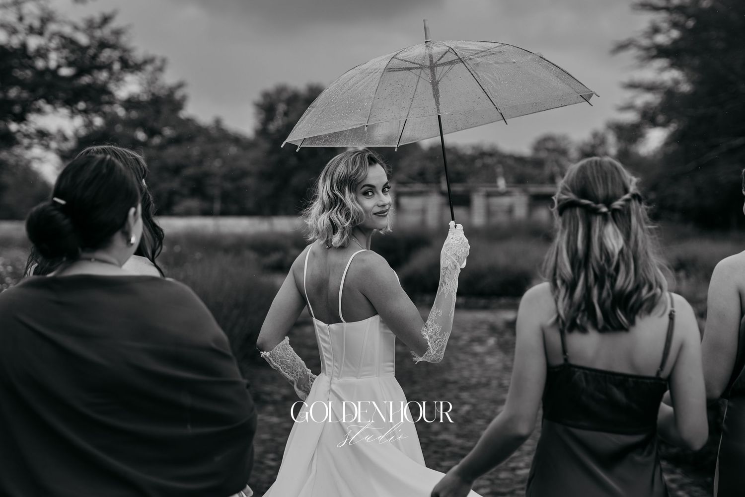 Wedding party walking with umbrellas during a rainy outdoor celebration.