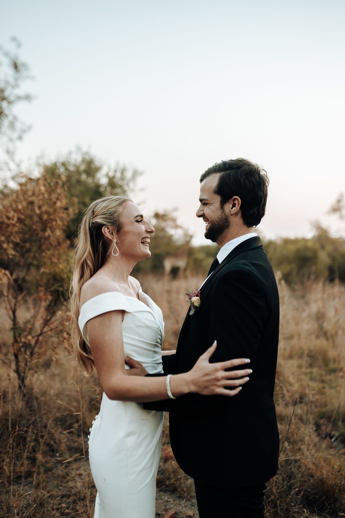 A joyful wedding portrait capturing laughter and love on a natural bush setting path.
