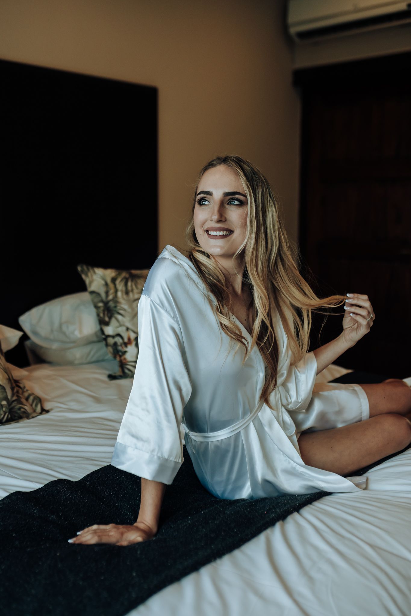 Morning wedding preparation scene in a cozy bedroom setting.