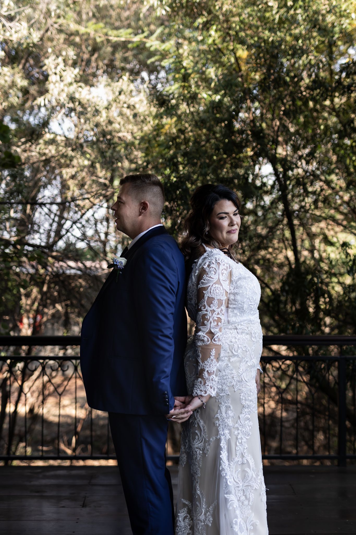 Stylish bride and groom stand back-to-back for dramatic outdoor portrait.