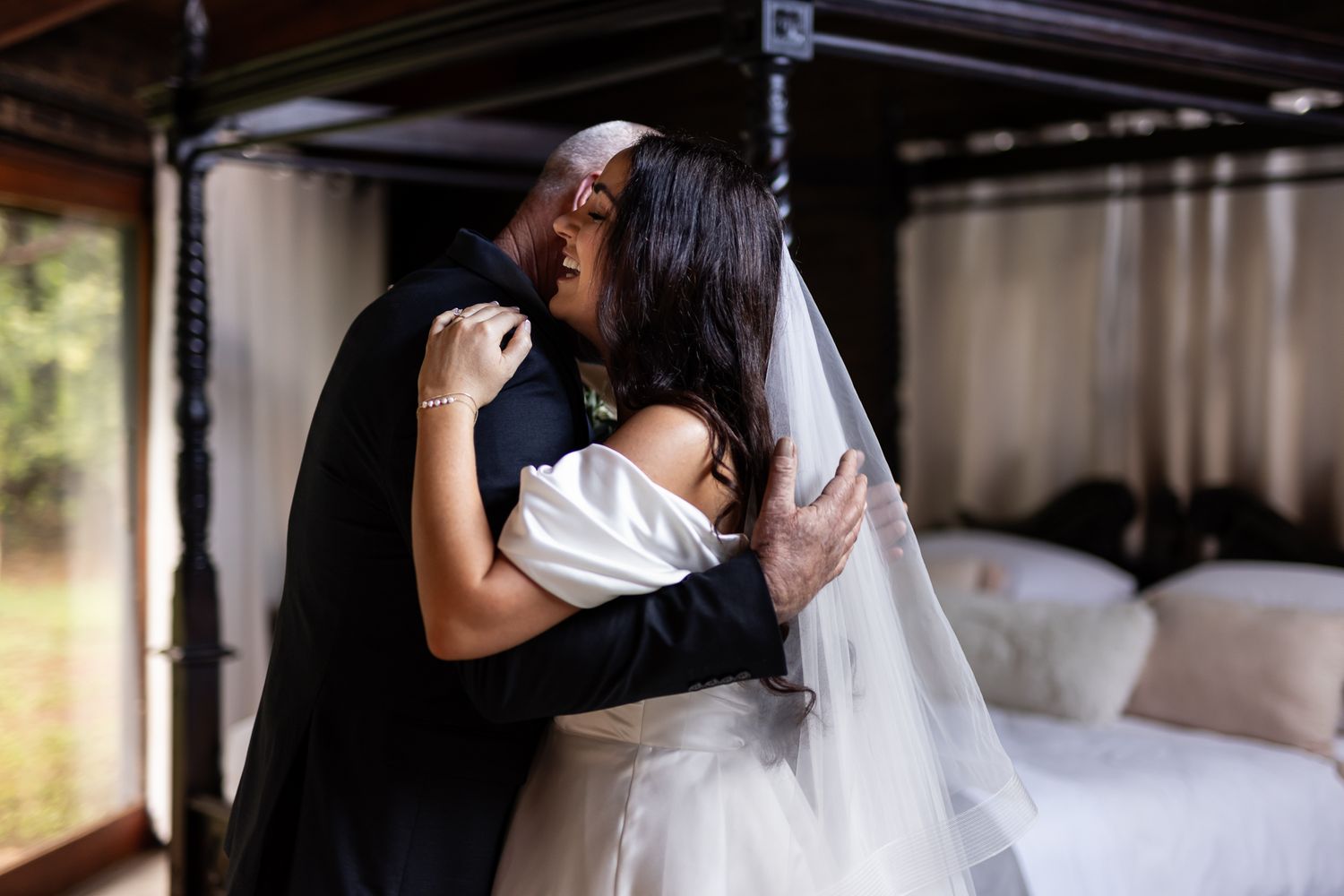 An intimate embrace between two people during a wedding moment in a bedroom setting.