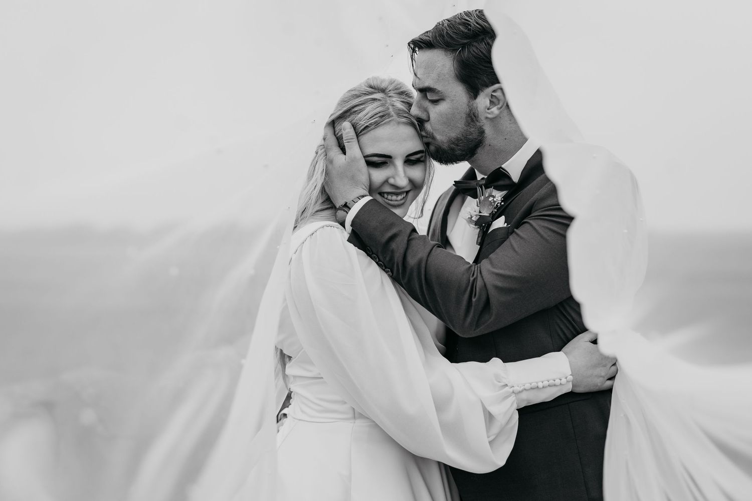 Intimate black and white portrait of newlyweds sharing tender moment during their wedding day.