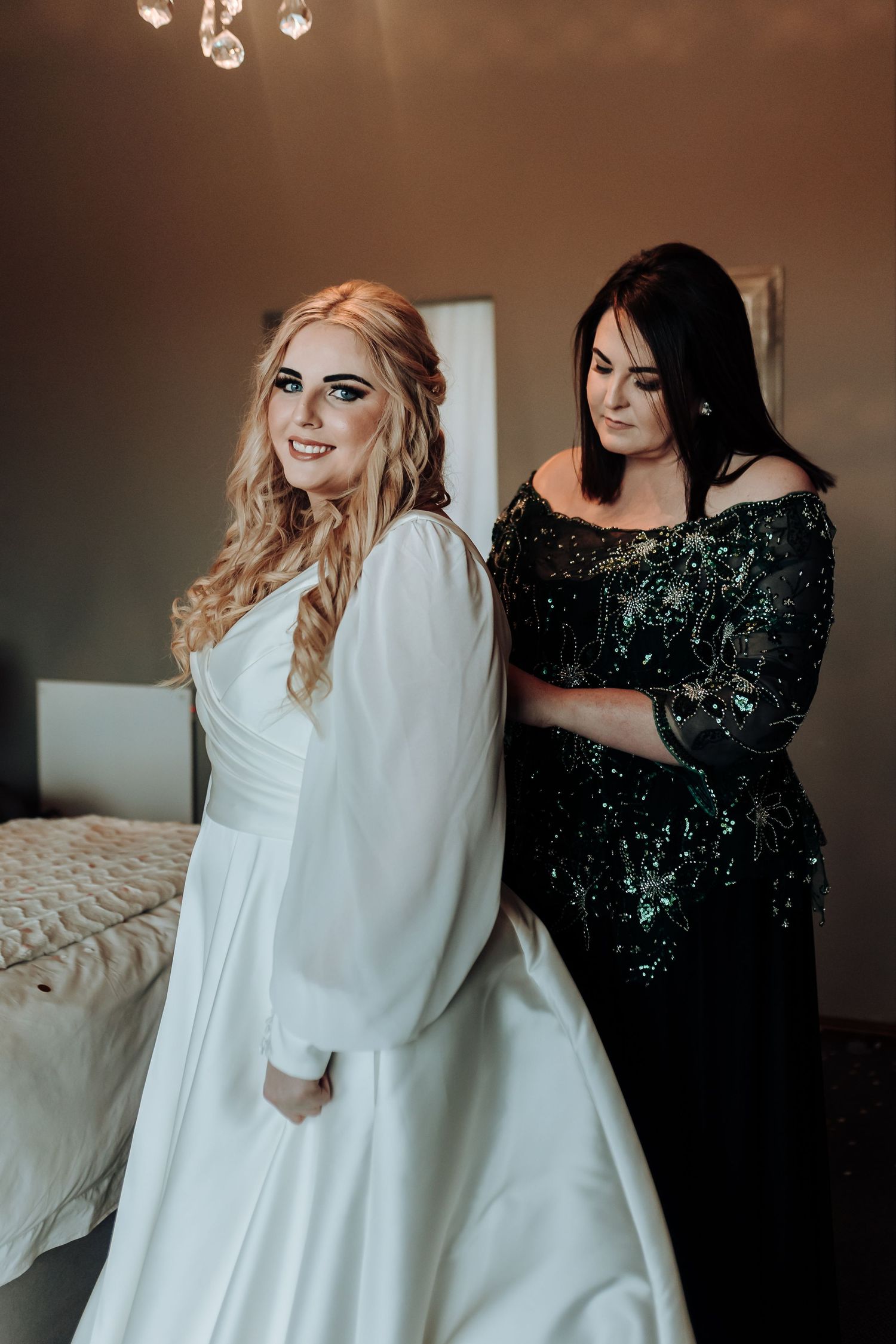 Two people share a special moment in formal wear, one in white and one in sparkly black.
