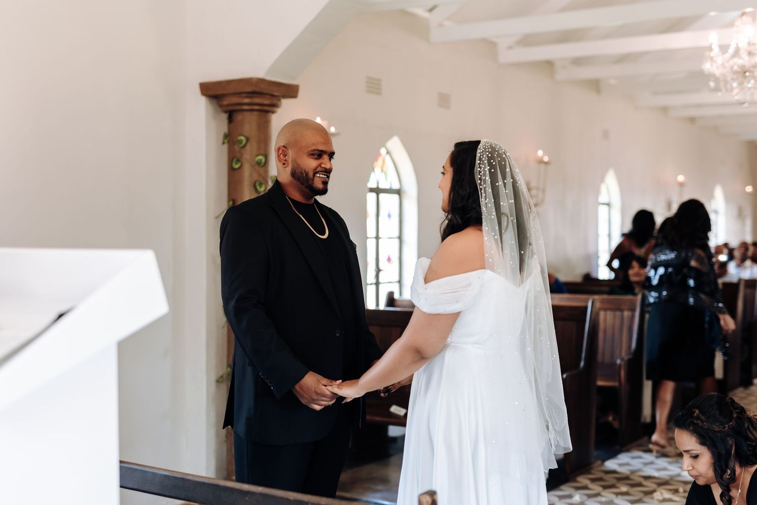 A couple exchanging vows during their wedding ceremony in a beautiful white chapel.