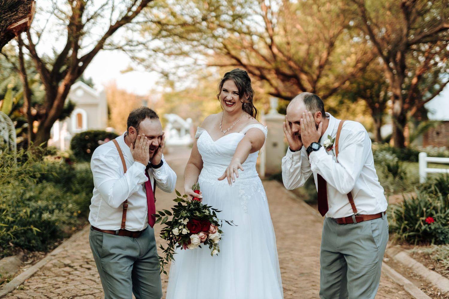 Fun candid moment with wedding party members on brick pathway.