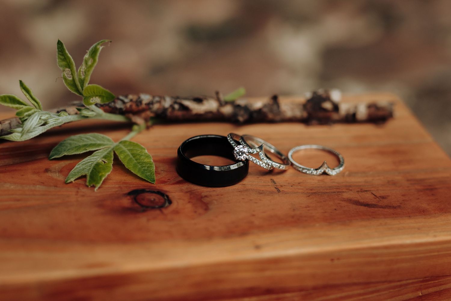 Marijuana buds and leaves arranged on a wooden surface with rolling papers and smoking accessories.