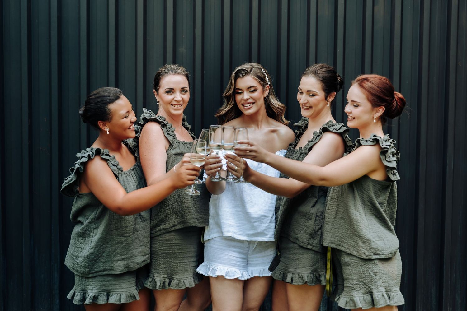 Bridesmaids in sage green dresses celebrate and pose together in a series of candid wedding party photos.