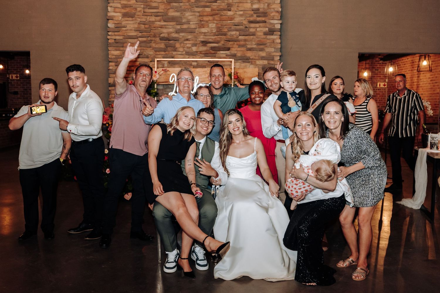 Wedding party and guests dancing and celebrating in an industrial-style reception venue.