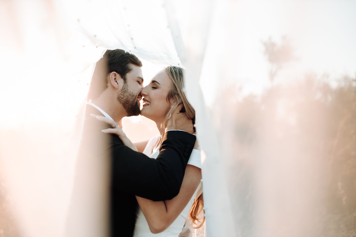 Intimate wedding portrait of a couple sharing a joyful moment in soft lighting.