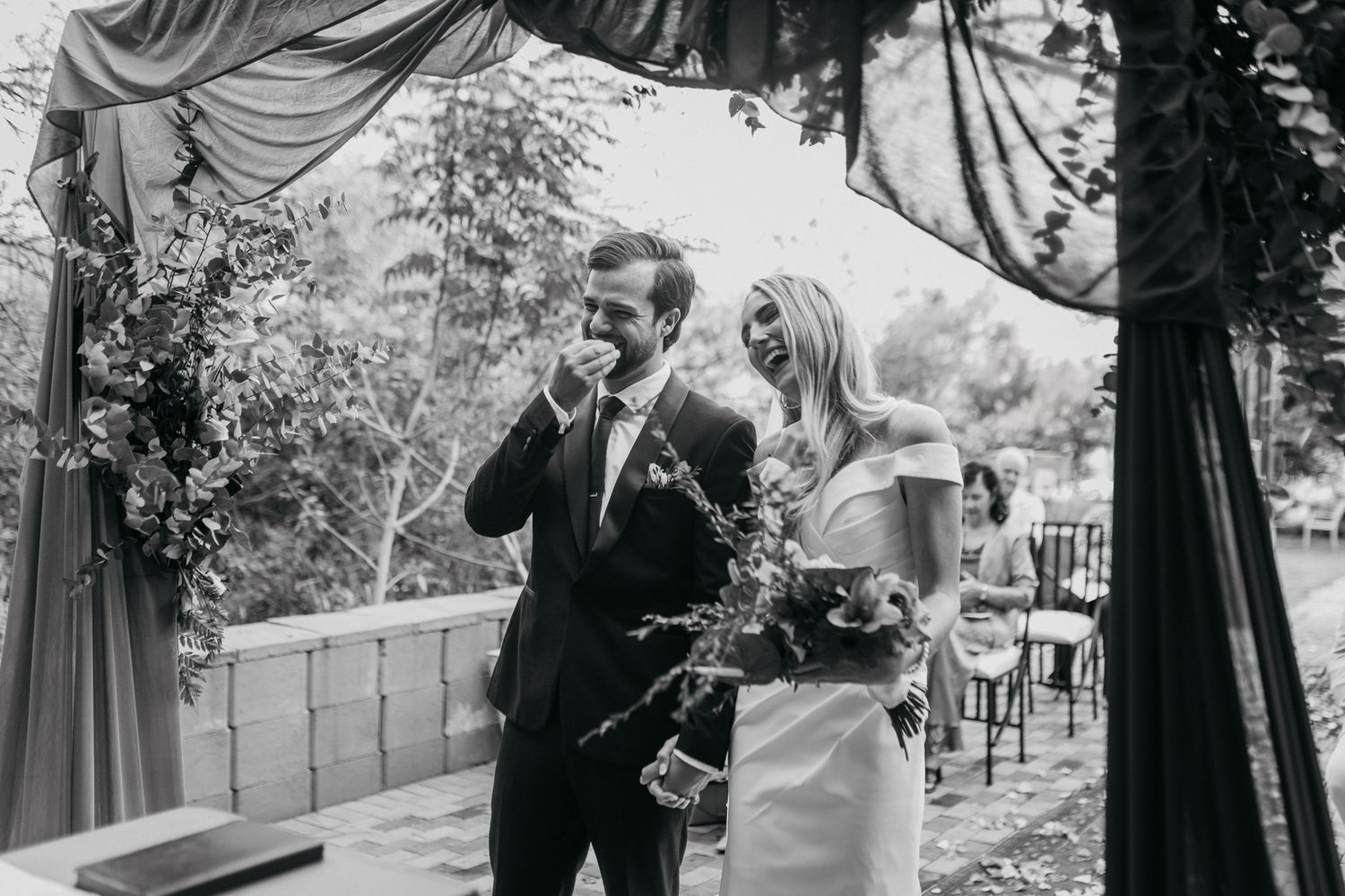 Black and white outdoor wedding moment under elegant draped fabric and natural surroundings.