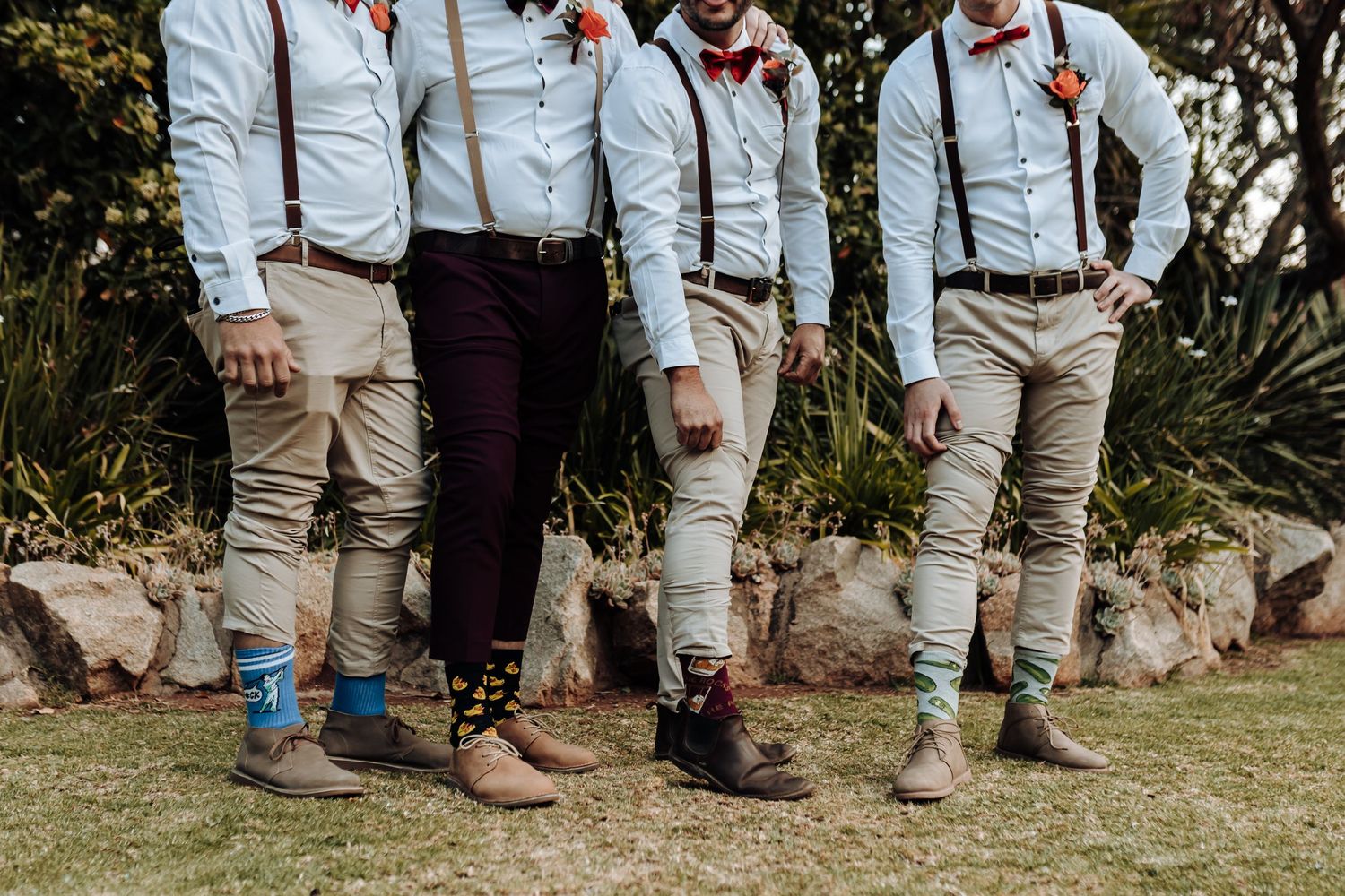 Stylish groomsmen showing off colorful socks with khaki pants and leather shoes.